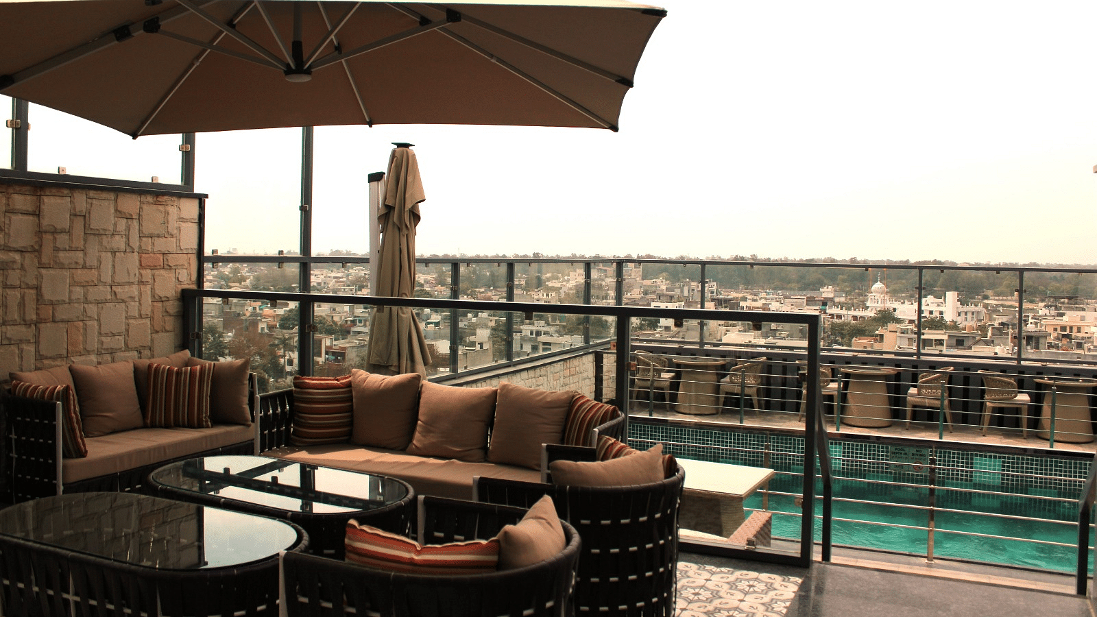 A rooftop lounge with a spacious patio and an adjacent swimming pool at BluSalzz Residence, Amritsar